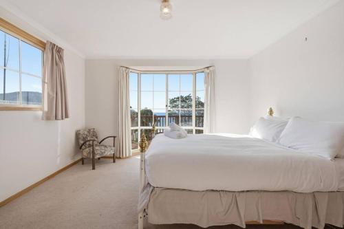 a white bedroom with a large bed and a window at Eaglehawk Neck Getaway in Eaglehawk Neck