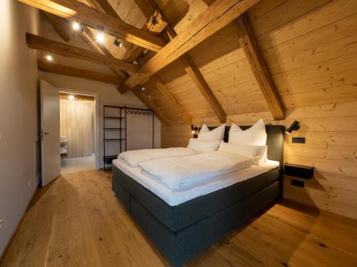 a large bed in a room with wooden ceilings at Fuxbau Allgäu in Argenbühl