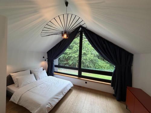a bedroom with a bed and a large window at Stodoły Północ in Debina