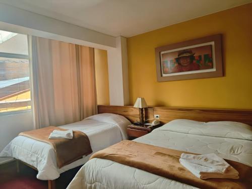 a hotel room with two beds and a window at Kaaro Hotel Suite in Puno