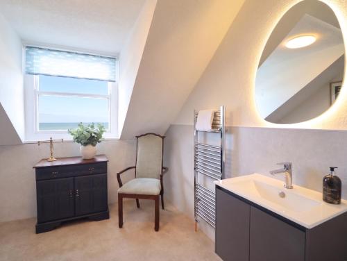 a bathroom with a sink and a chair and a mirror at Sea View, East Parade in Llandudno