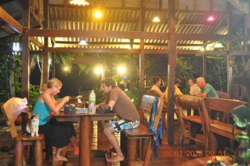 a man and woman sitting at a table in a restaurant at Frog Garden Hut in Ko Phayam