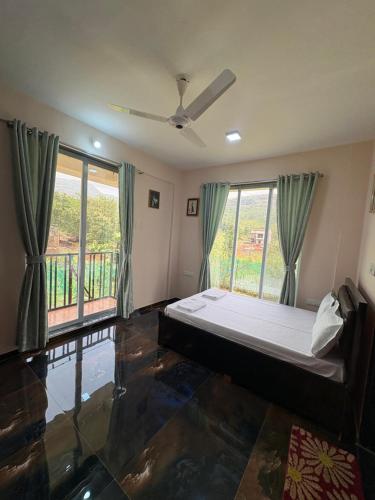 a bedroom with a bed and a balcony at kailasa Villa in Karjat