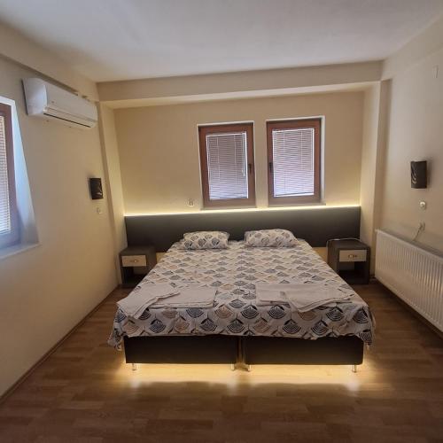 a bedroom with a bed and two windows at Villa Rimari in Ohrid