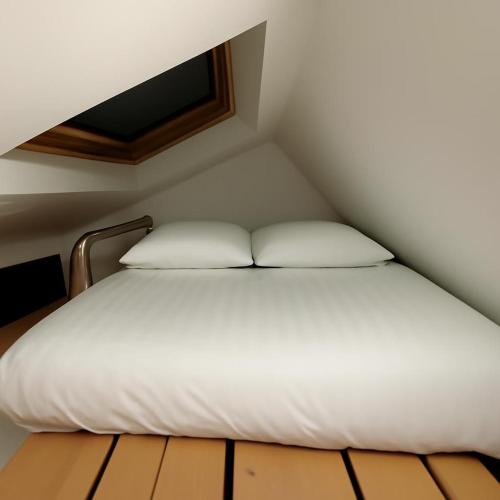 a bed with white sheets and pillows in a room at Harbour view Tree House in Cobh