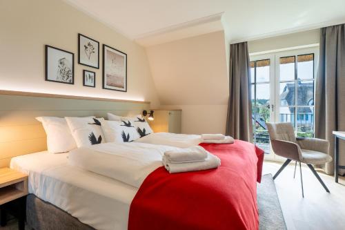 a bedroom with a large bed with a red blanket at Apartmenthaus Resort Kranichsruh in Fuhlendorf