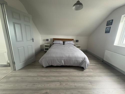 a white bedroom with a bed in a attic at Lar Na Cluaine in Kilmurry