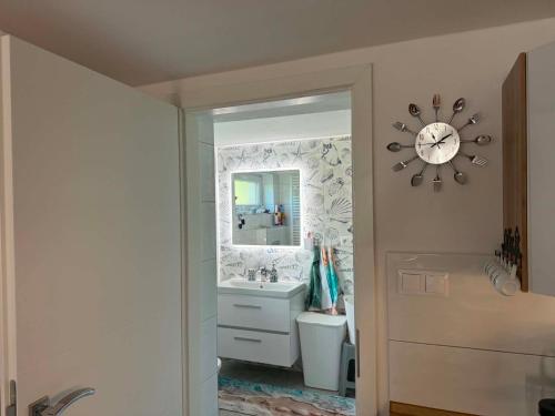 a bathroom with a sink and a clock on the wall at Apartmán U našich in Jeseník