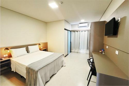 a hotel room with a bed and a television at Hotel da Vila in Vila Bela da Santíssima Trindade