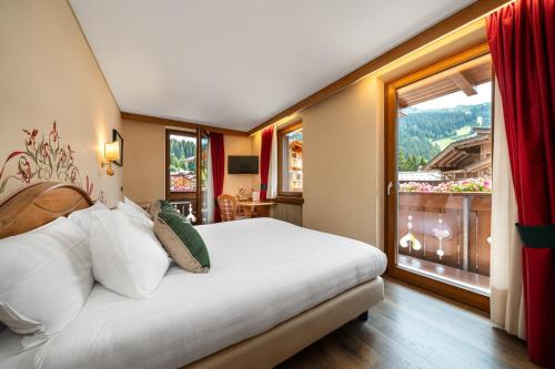 a bedroom with a large bed and a large window at Hotel Garnì La Montanara in Madonna di Campiglio