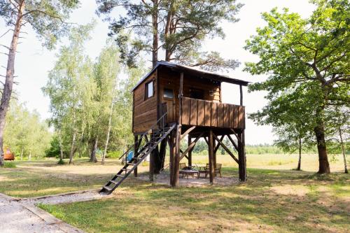 a tree house with a ladder in a park at Tesla`s Valley in Smiljan