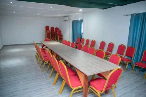 a conference room with a long table and red chairs at Résidences Hôtel Nanga & Restaurant in Korhogo