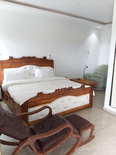 a bedroom with a wooden bed and a chair at Résidences Hôtel Nanga & Restaurant in Korhogo