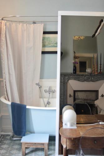a bathroom with a tub and a table and a mirror at Demeure Les ragottières in Le Plessis