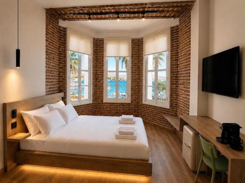 a bedroom with a bed and a desk and windows at Neossiko Chios in Chios