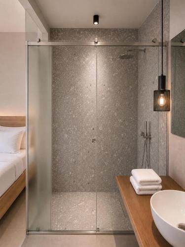 a bathroom with a glass shower and a sink at Neossiko Chios in Chios