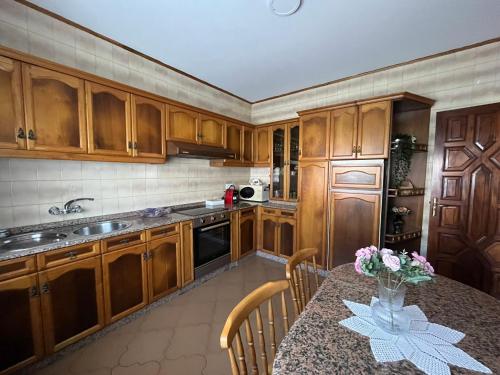 a kitchen with wooden cabinets and a table with flowers on it at Casa Ezaro in Dumbría