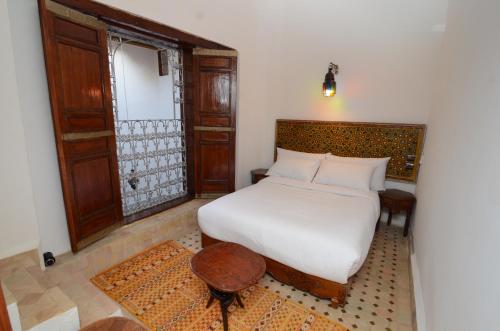 a bedroom with a white bed and a wooden door at Le Cèdre D'argent in Fès