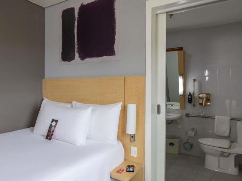 a bedroom with a bed and a bathroom with a toilet at Ibis Hermosillo in Hermosillo