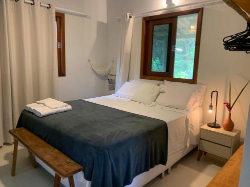 a bedroom with a bed with a window and a bench at Casa Raiz 1 Moreré - A 3min da praia in Moreré