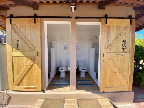 a bathroom with two toilets with wooden doors at Glamping Rivera del Mar - RV Park in Loreto