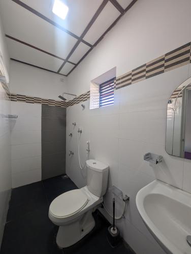 a white bathroom with a toilet and a sink at AmeriLanka Transit Hotel in Seeduwa