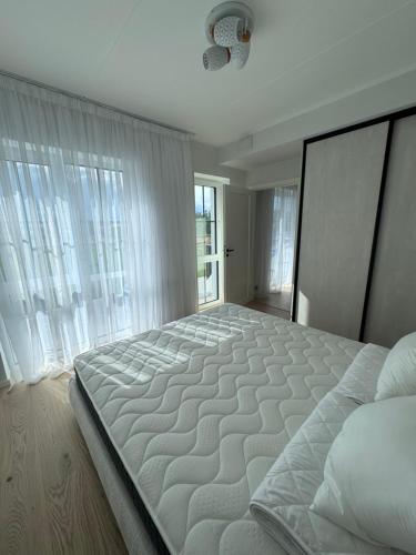 a large white bed in a room with windows at Kukerpuu Kinnisvara in Raadi
