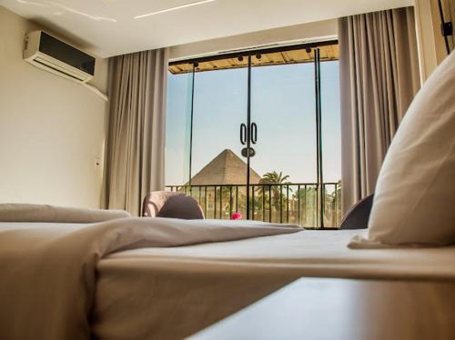 a hotel room with a bed and a large window at Miracle Pyramids View Hotel in Giza