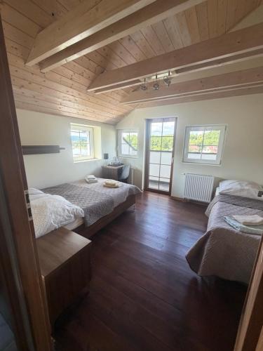 two beds in a room with wooden floors and windows at Pokoje Gościnne Nad Zalewem w Starej Morawie in Stronie Śląskie