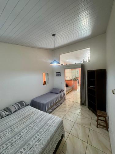 a bedroom with two beds and a living room at Chalé em Maresias - Quintal Privativo - Pet Friendly 4 Hóspedes in Maresias