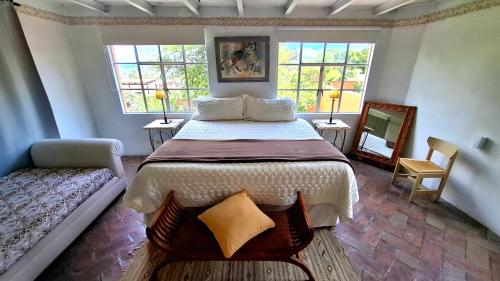 a bedroom with a large bed and two windows at Suites Santo Domingo in San Miguel de Allende