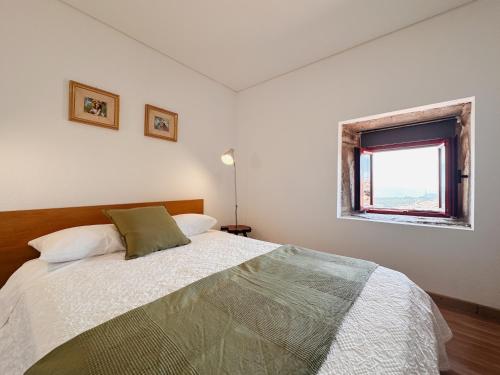a white bedroom with a bed and a window at Douro Feels Like Home in Fontelo