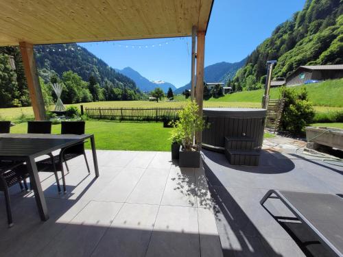a patio with a table and chairs and mountains at Haus Valtellina in Sankt Gallenkirch