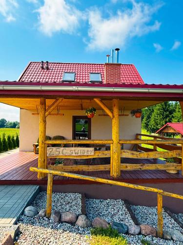 a house with a wooden deck with a red roof at Domek nad Oczkiem Wodnym in Giżycko