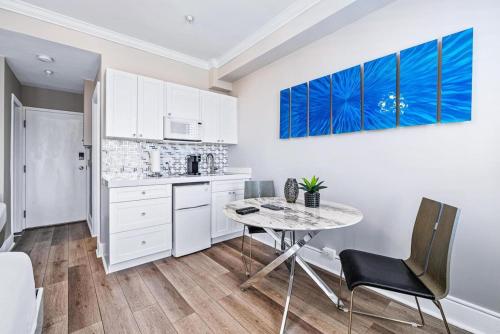 a kitchen with white cabinets and a table and chairs at 1BR Retreat with Private Terrace in Palm Beach