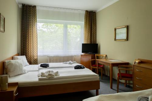 a hotel room with two beds and a desk and a window at Penzion Hubert Františkovy Lázně in Františkovy Lázně