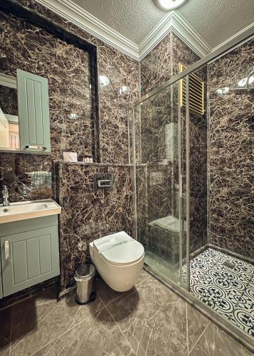 a bathroom with a toilet and a glass shower at Çamra Otel in Armutlu