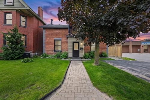 a brick house with a walkway in front of a yard at The 1883 Century Flat Suite in Collingwood