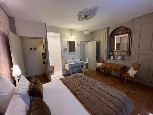 a bedroom with a large bed and a bathroom at La Demeure d'Euphrosine in Fresnay-sur-Sarthe