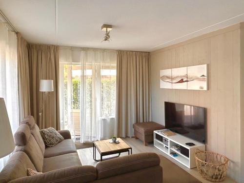 a living room with a couch and a flat screen tv at Luxe Duinsuite in Groet