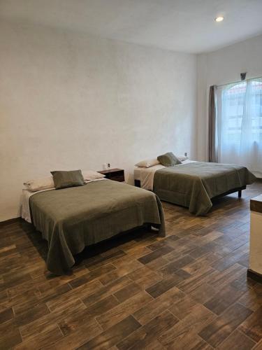 two beds in a room with wooden floors at Hotel del Carbón in Villa del Carbón