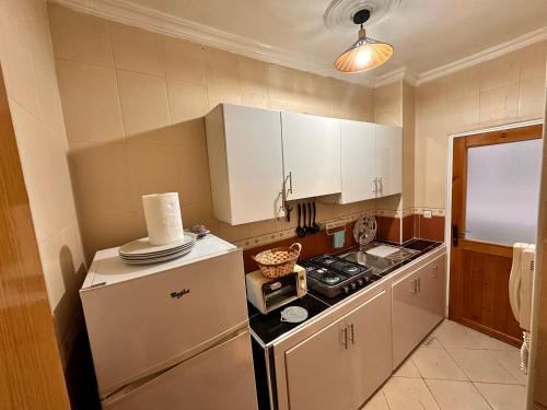 a kitchen with white cabinets and a stove and a refrigerator at Appartement Nadin in Martil