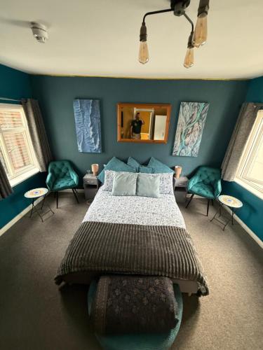 ein Schlafzimmer mit einem Bett, blauen Wänden und Stühlen in der Unterkunft Sullys in Hastings