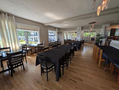 a dining room with tables and chairs and windows at Auberge de nos Aieux in Les Éboulements