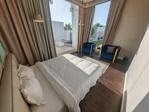 a bedroom with a bed and a large window at Al Salateen Villas Resort in Al ‘Ammārīyah