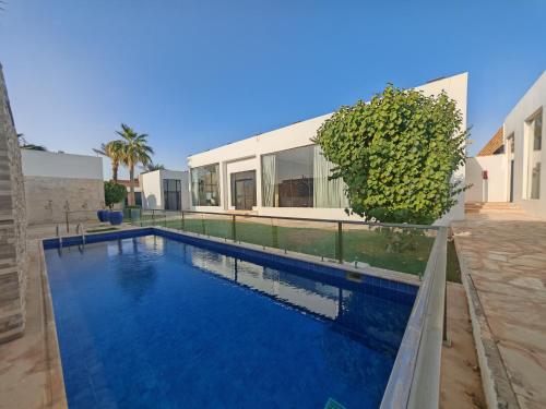 a swimming pool in front of a house at Al Salateen Villas Resort in Al ‘Ammārīyah