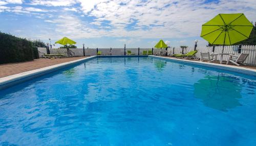 a large blue swimming pool with chairs and umbrellas at Auberge de nos Aieux in Les Éboulements