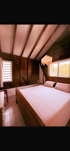 a large bed in a room with two windows at Caress antillaise in Deshaies