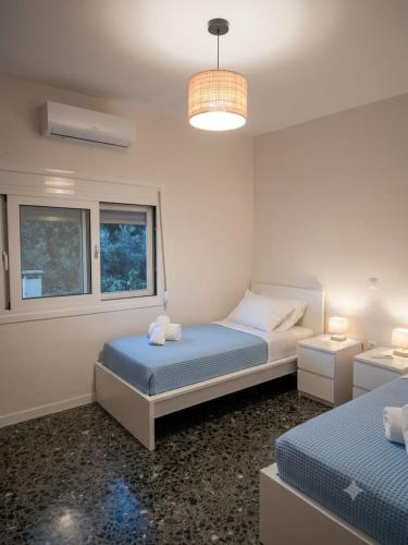 a bedroom with two beds and a chandelier at LagonisiSunsetHouse in Kalívia Thorikoú