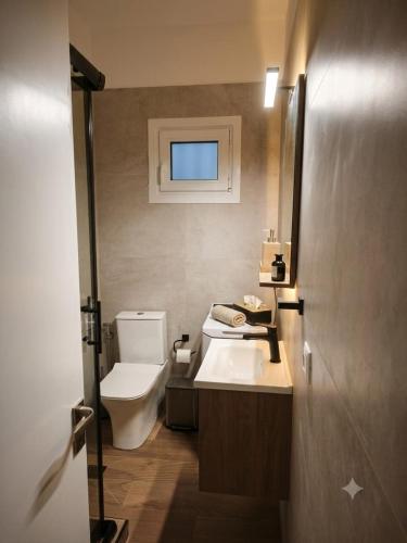 a bathroom with a white toilet and a sink at LagonisiSunsetHouse in Kalívia Thorikoú